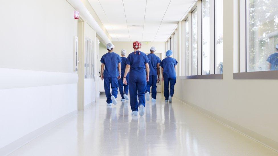 Surgical team walking down hospital corridor - stock photo