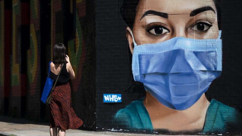 A woman takes a photo of graffiti on Brick Lane in East London on April 23, 2020