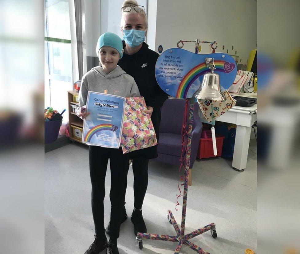 Ruby and her mum with the bell and a certificate