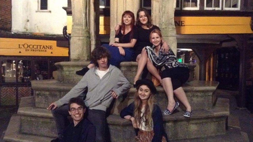 People sitting on the Buttercross after a night out