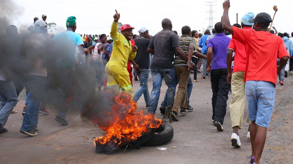 Protesting residents place burning tyres to create a roadblock as they march on the main road leading into the town of Bronkhorstspruit during a protest over poor public service delivery