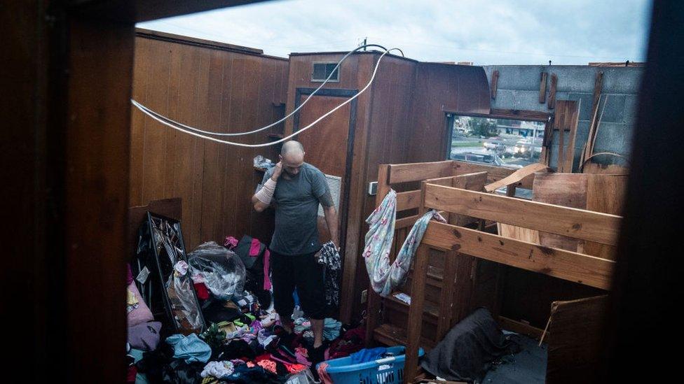 A man surveys the damage to his home, which now lacks a roof.