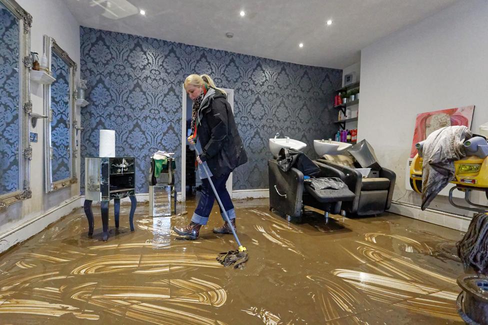 Laura Court mops up the floor of a hair dressers in Nantgarw, Wales.