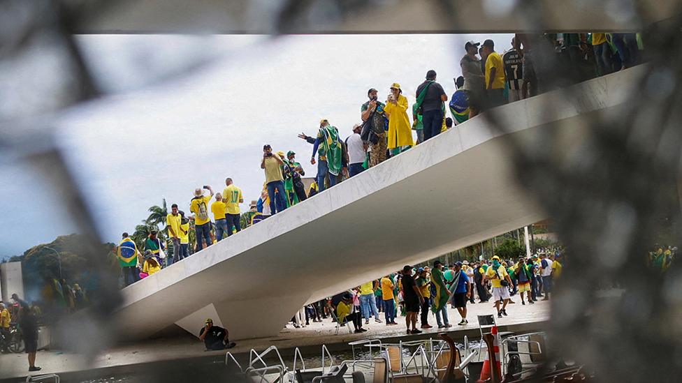 Supporters of Brazil's former President Jair Bolsonaro are pictured through broken glass as they hold a demonstration against President Luiz Inacio Lula da Silva, in Brasilia, Brazil, January 8, 2023