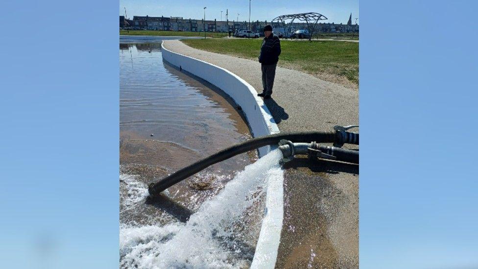 A member of Redcar Model Boat Club observing the test refill. Water is flowing into the structure from a pipe above.