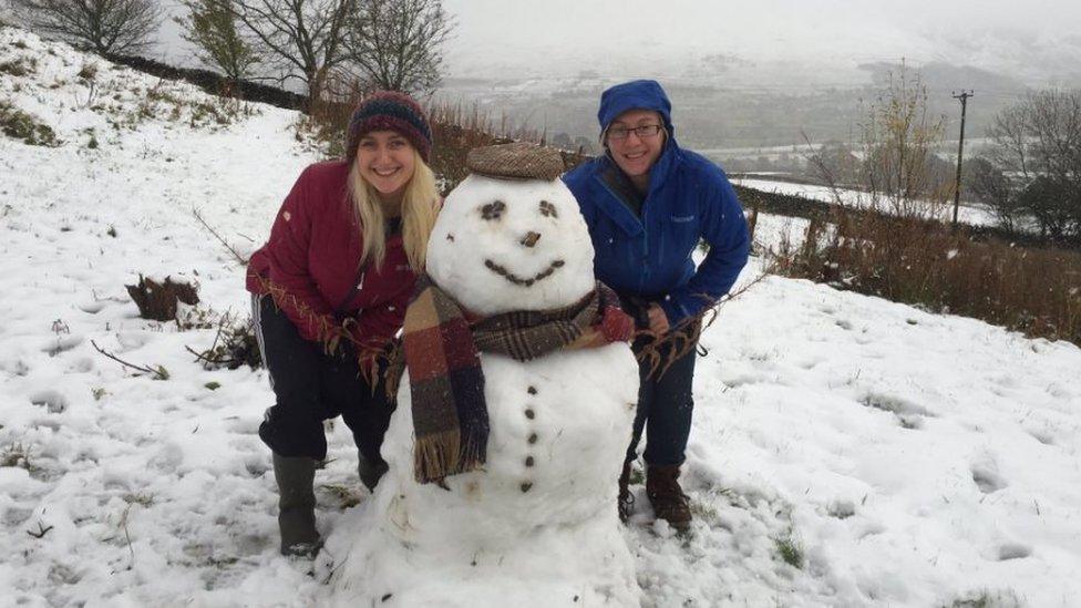 Two women pose with a snowman