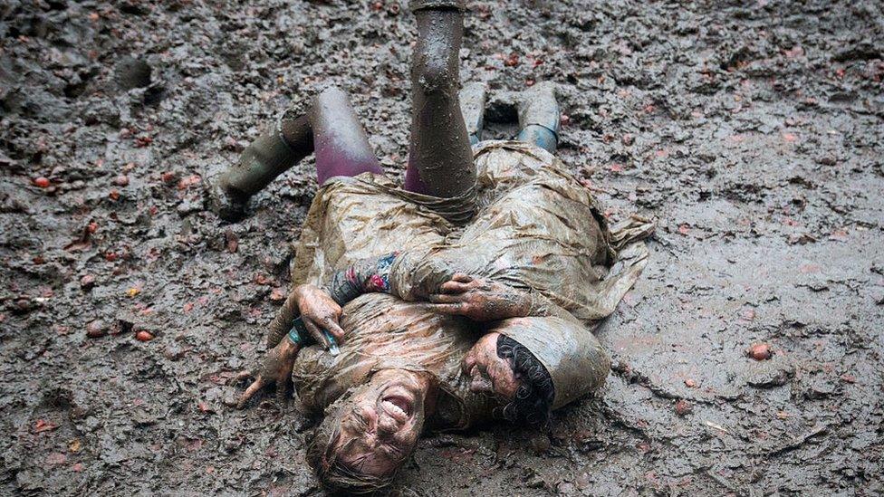 Two festival revellers roll in the mud at Glastonbury.