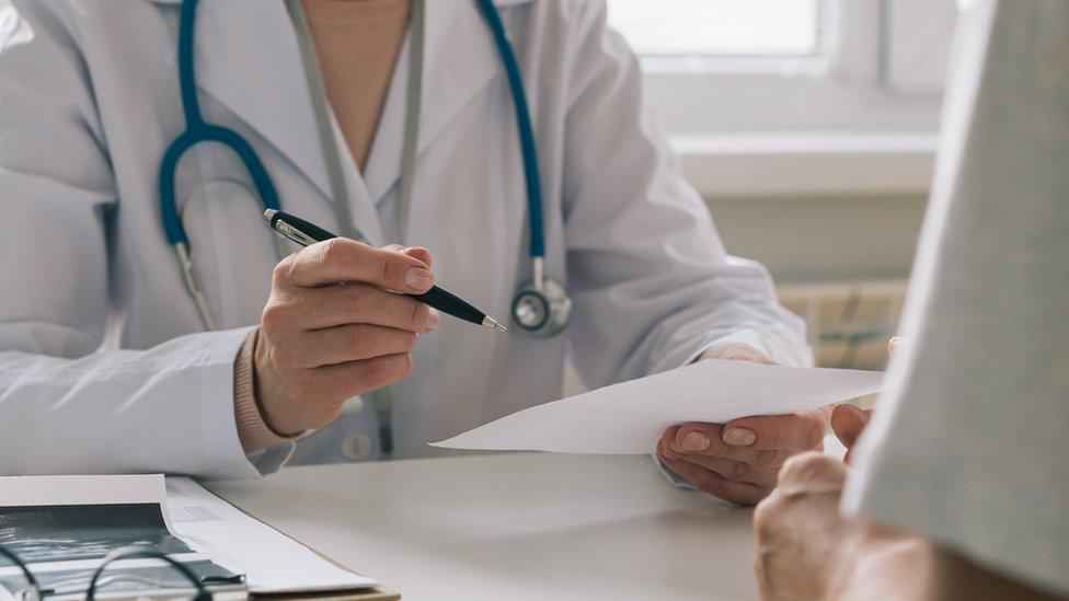 Unrecognizable doctor consulting patient. Giving piece of paper with instructions and recommendations - stock photo