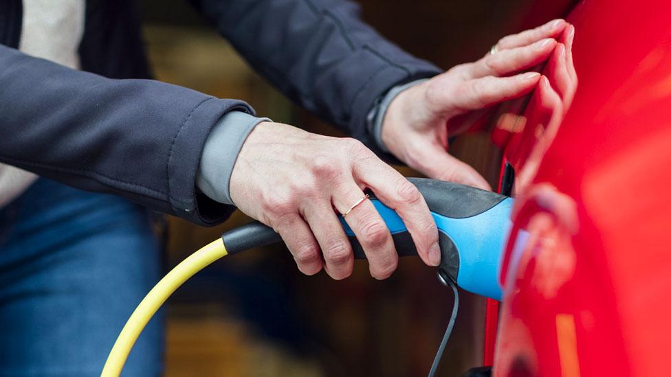 Stock image of a woman charging an electric car