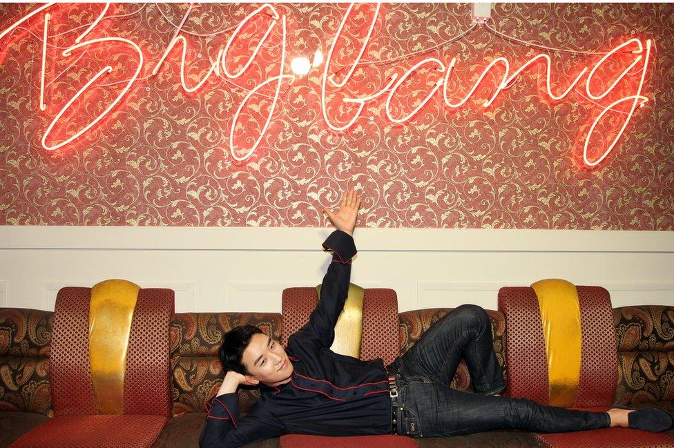 Bigbang's Seungri lies down in front of a neon sign reading 'bigbang'