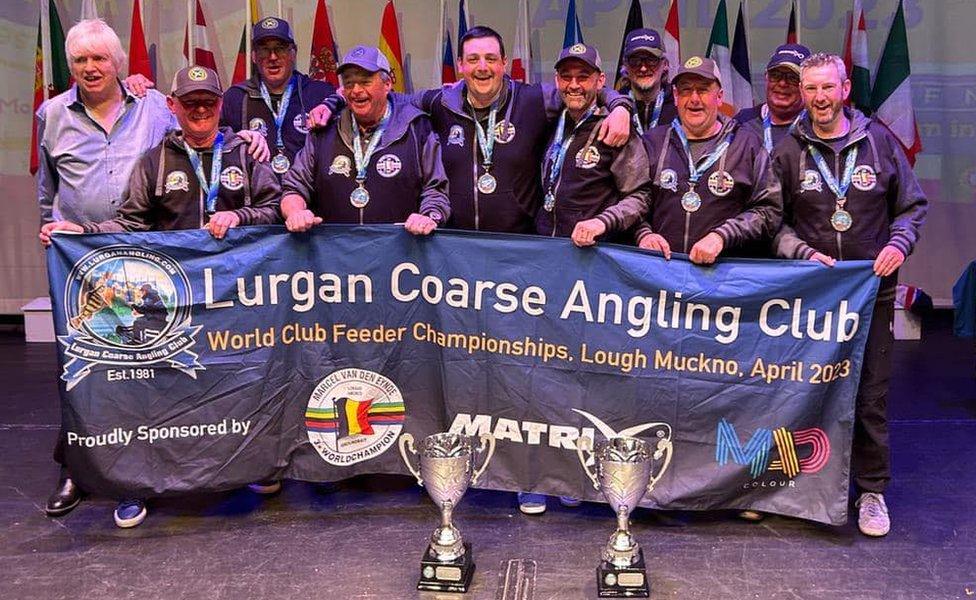 Lurgan Coarse Angling Club members posing with their trophies and holding a banner that reads: Lurgan Coarse Angling Club - World Club Feeder Fishing Championships, Lough Muckno, April 2023