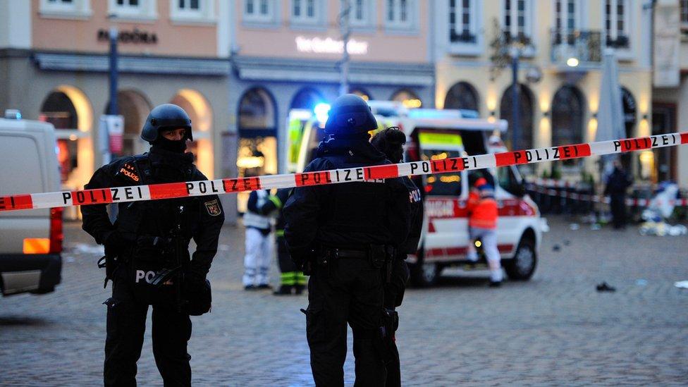 Police officers and forensic investigators and an ambulance work at one of the scenes in Trier