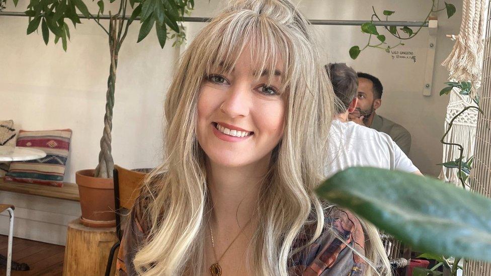 A woman with long blonde hair smiling at the camera