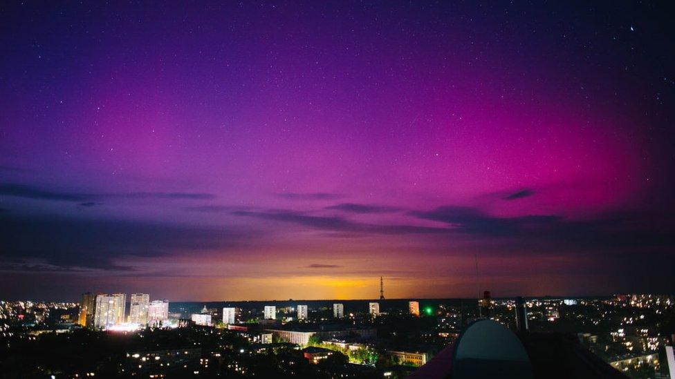 The moon is being illuminated by light reflected from the Earth and is surrounded by the northern lights, in Kharkiv, Ukraine