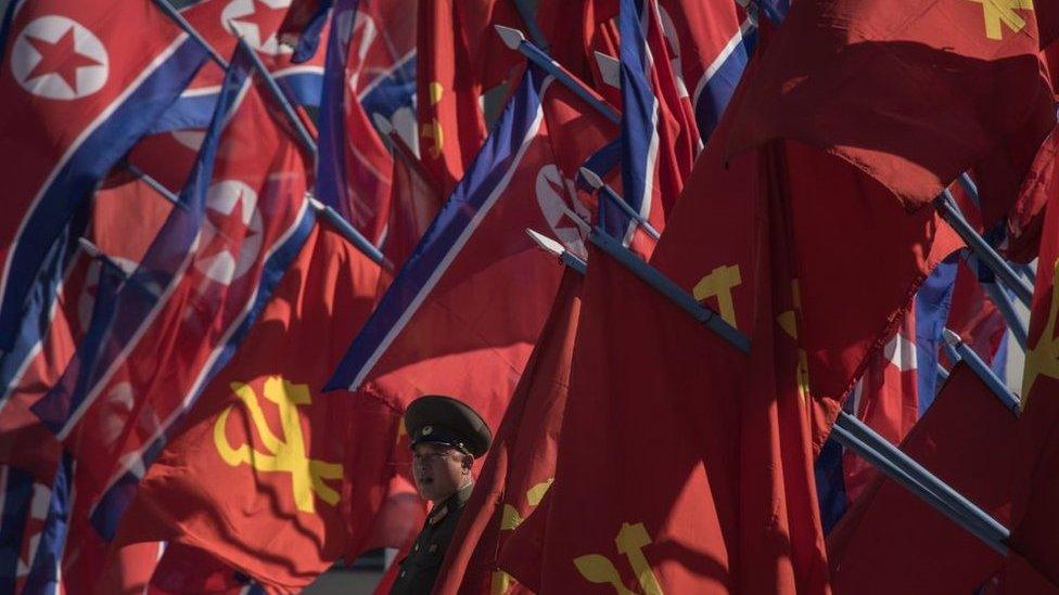 A Korean People's Army (KPA) soldier stands between flags prior to an opening ceremony for the Ryomyong Street housing development in Pyongyang on 13 April 2017.