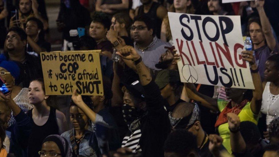 Protestors hold up banners saying "stop killing us" outside Charlotte Police Station