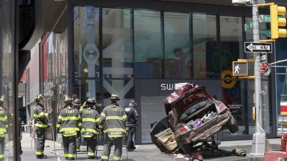 Firefighters look on at a crashed car in New York