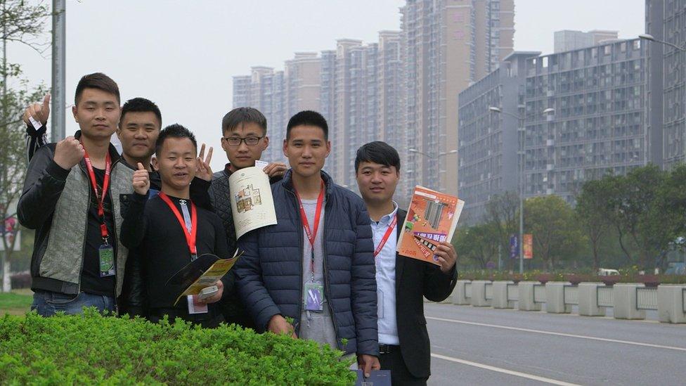 A group of real estate agents pose by the road in Huaqiao, just outside Shanghai, where they hand out flyers to passing motorists