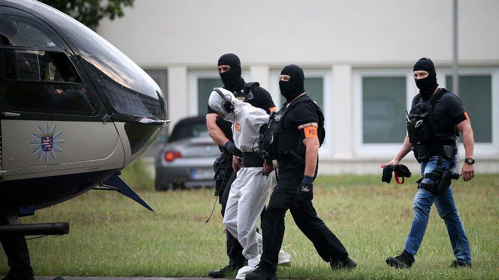 Police officers of a special unit escort Iraqi asylum seeker Ali Bashar, who is suspected of having killed a German teenage girl, to a helicopter in Wiesbaden, western Germany, on June 10, 2018