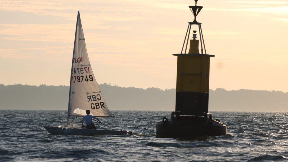 Harry White sailing in his dinghy next to a buoy