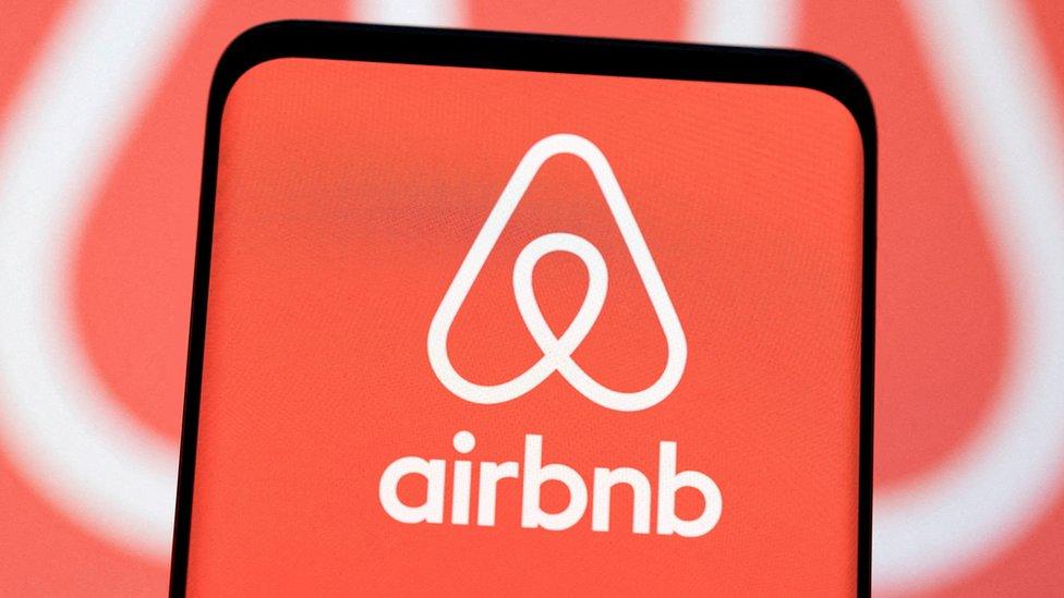 The Airbnb logo is seen displayed in an illustration.