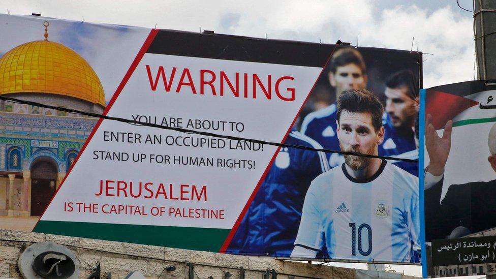 A picture taken on June 5, 2018, shows a poster erected on a main street in the West Bank town of Hebron next to a portrait of the Palestinian president Mahmud Abbas