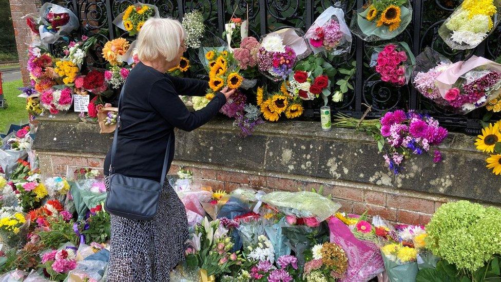 Lady placing flowers in railings at Sandringham House