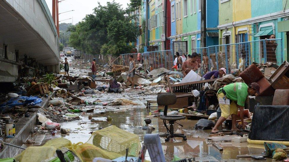 Residents gather mud-filled debris taken from their houses