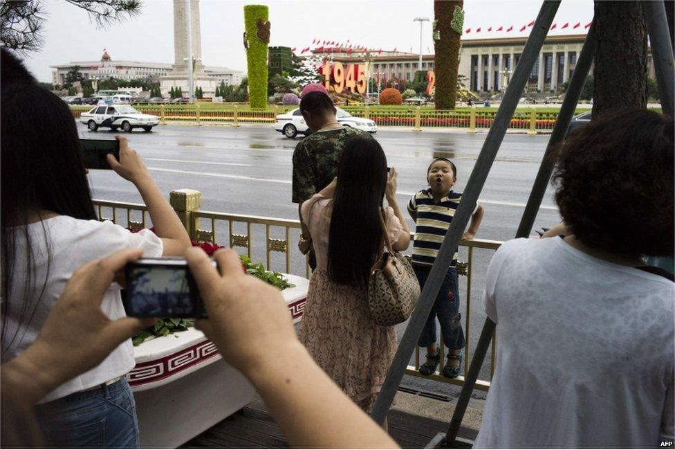 Onlookers take photographs near to an area where access has been blocked to the public in Tiananmen Square in China's capital Beijing on 1 September 2015, prior to a military parade to be held on 3 September to mark the victory over Japan and the end of World War Two.