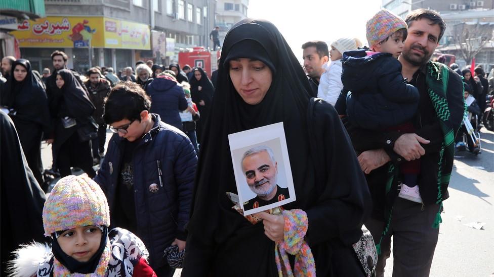 An Iranian woman holds a photo of picture of Iranian General Qasem Soleimani at his funeral in Tehran (6 January 2020)