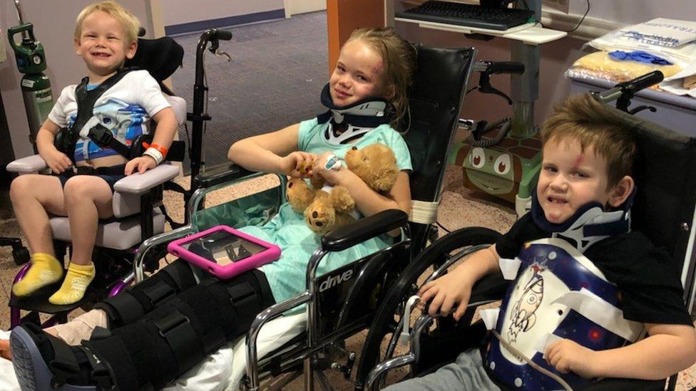 All three children sit together in wheelchairs.