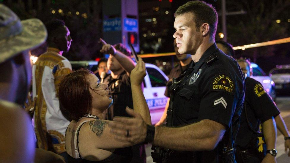 Woman takes photograph of police officer on street in Dallas, Texas - July 2016