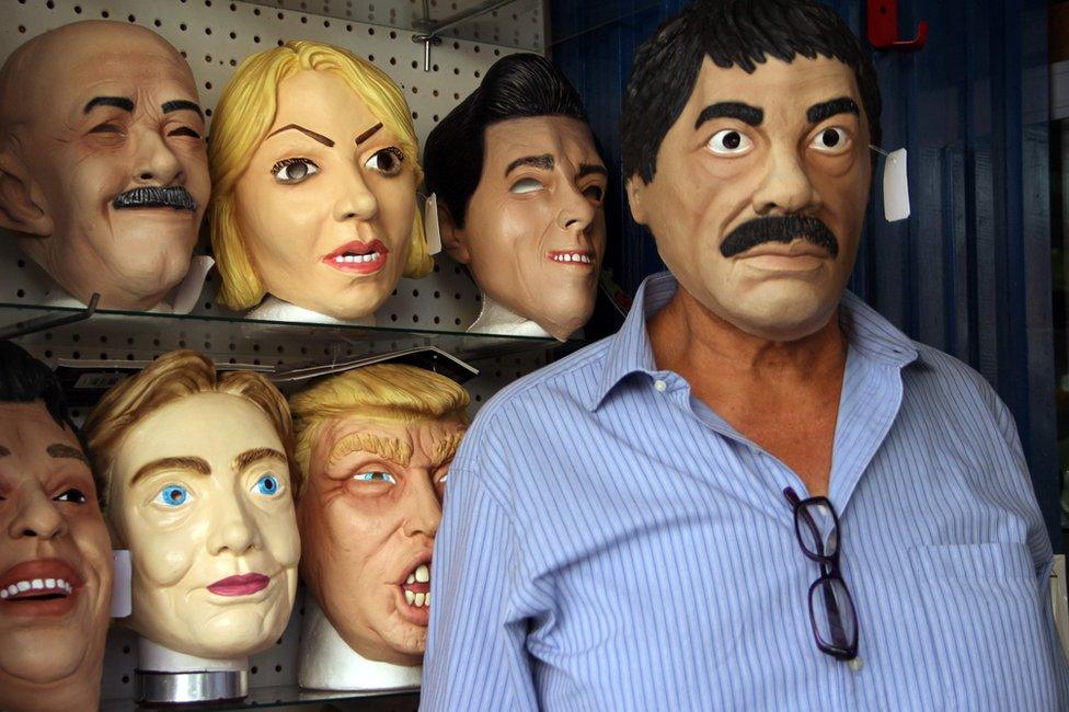 Shopkeeper Manuel Robles (R) poses with a latex mask depicting Mexican drug trafficker Joaquin Guzman Loera -aka "El Chapo"- for sale for the upcoming Day of the Dead, in Ciudad Juarez, Chihuahua State, Mexico, 25 October