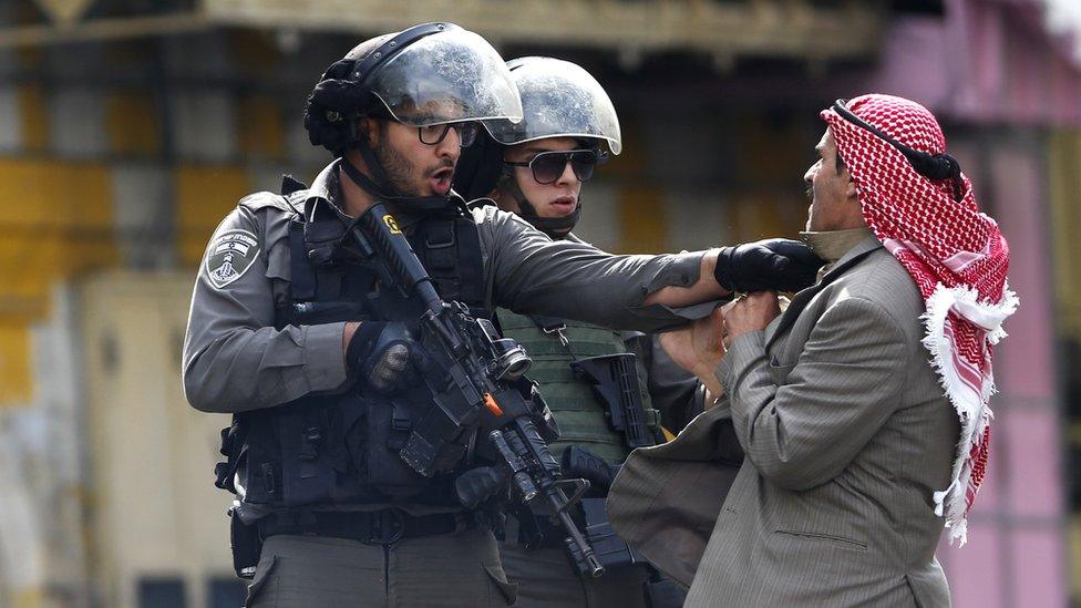 A Palestinian is pushed by an Israeli policemen amid clashes in Hebron, West Bank, Saturday, Oct. 10, 2015.