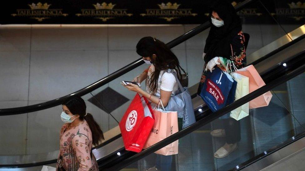 Customers carry shopping bags at a mall after the government eased a nationwide lockdown imposed as a preventive measure against the COVID-19 coronavirus, in Islamabad on May 18, 2020