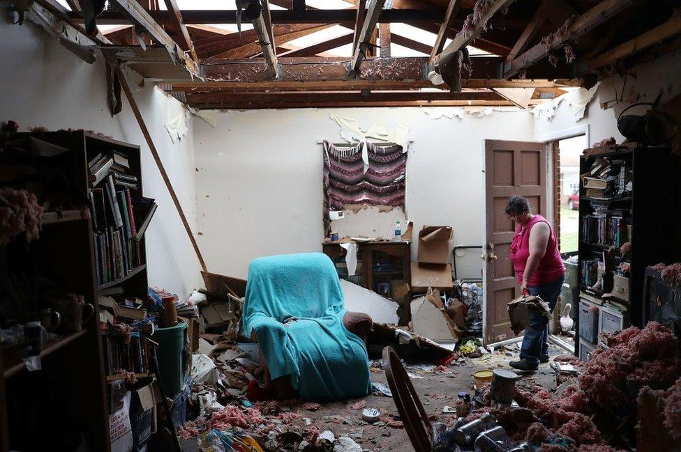 A Panama City resident begins cleaning her home, which has had the roof blown off.