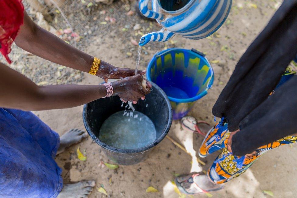 A woman washes her hands with soap and water in Norandé