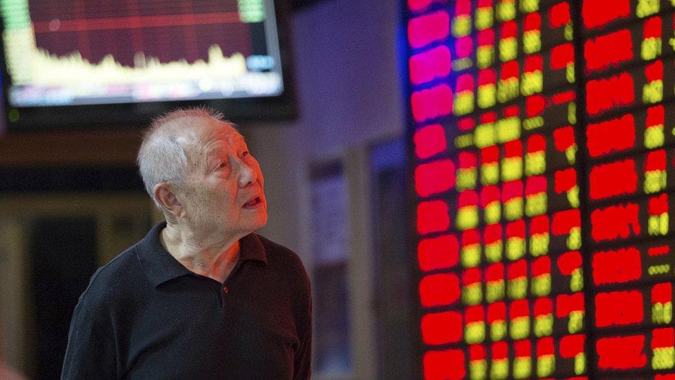 An investor walks past an electronic board in Nanjing, Jiangsu province on 20 September, 2015