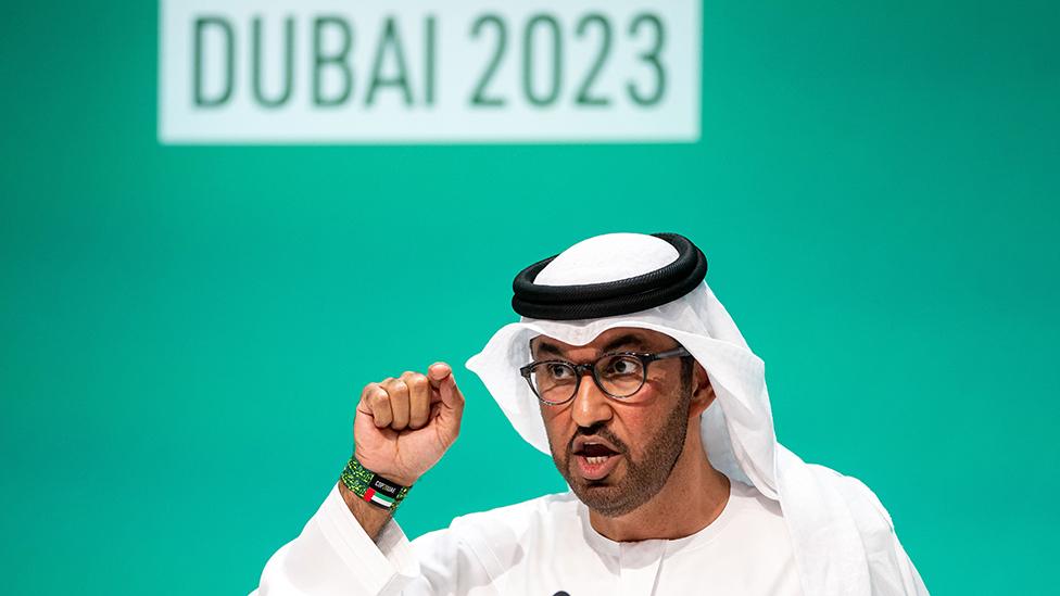 Dr. Sultan Ahmed Al Jaber, President-Designate of COP28 and UAE's Minister for Industry and Advanced Technology, gestures at a press conference, with 'Dubai 2023' written on the screen behind