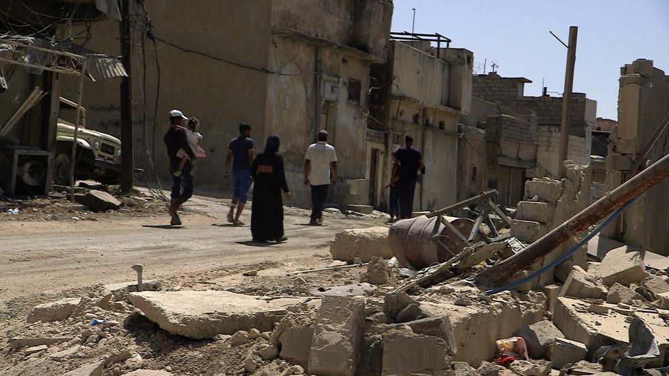 Ishar, a mother-of-four whose husband was killed by IS during the battle for Mosul, walks through the Old City with her children