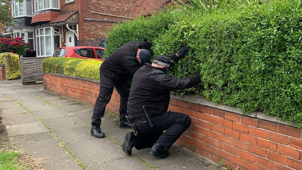 Officers search a hedge