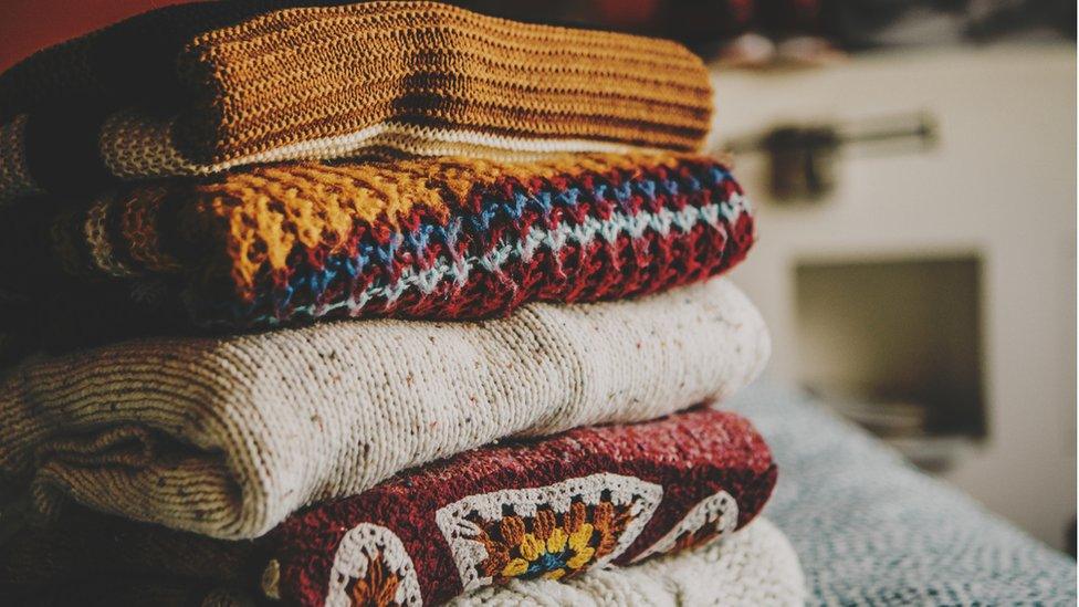 Cozy fall sweaters folded and stacked up on table