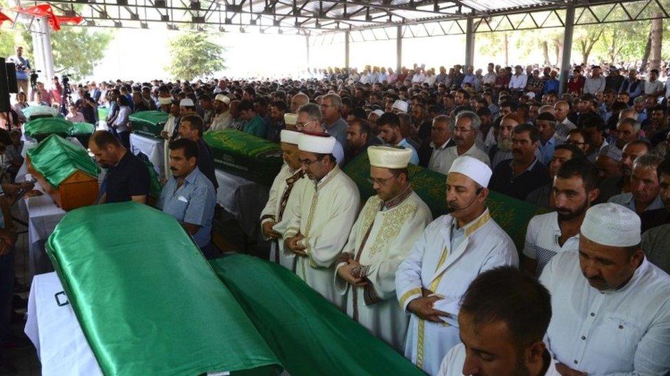 Imams lead the prayers as mourners gather for the funeral of victims of the attack on a wedding party