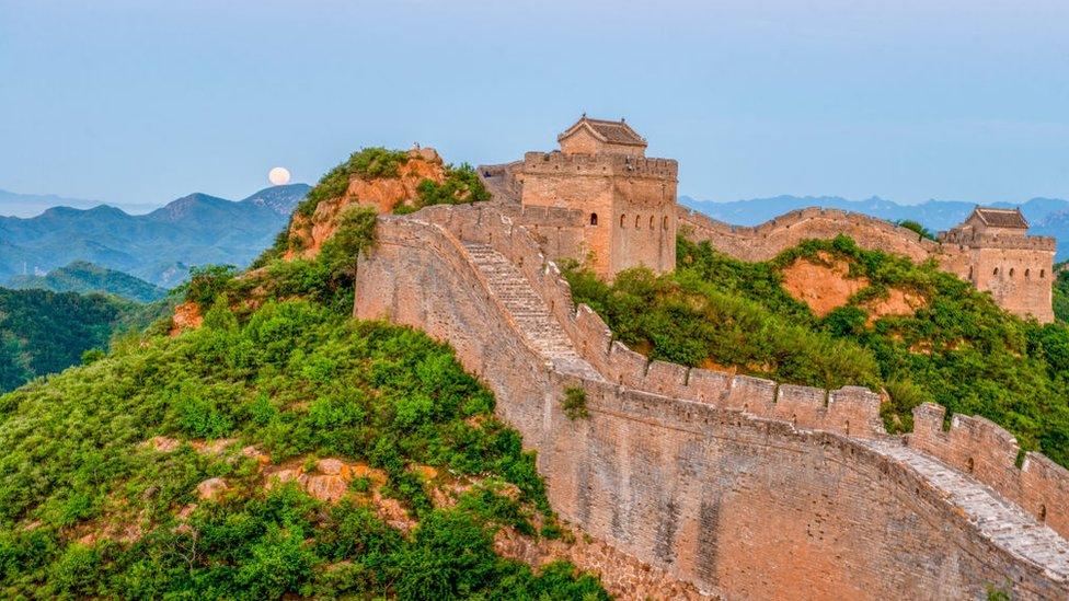 The full moon sets behind the Great Wall of China on the morning of July 14, 2022.