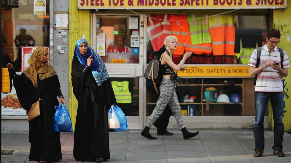 women wait to cross a road in London