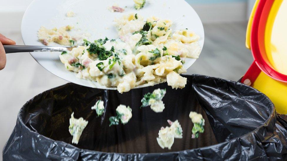 Food being scraped into black bin