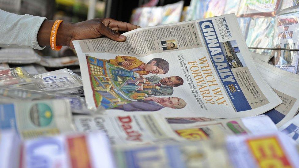 A newspaper vendor arranges copies of China's Africa edition of its daily newspaper