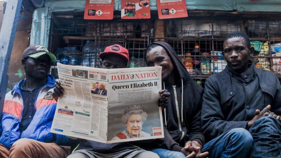 Locals reading a newspaper with a tribute to the Queen on the front page