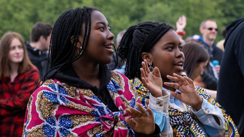 Two women in colourful wraps watch the music