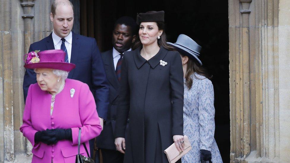 Duchess of Cambridge wearing a black coat and hat with baby bump visible